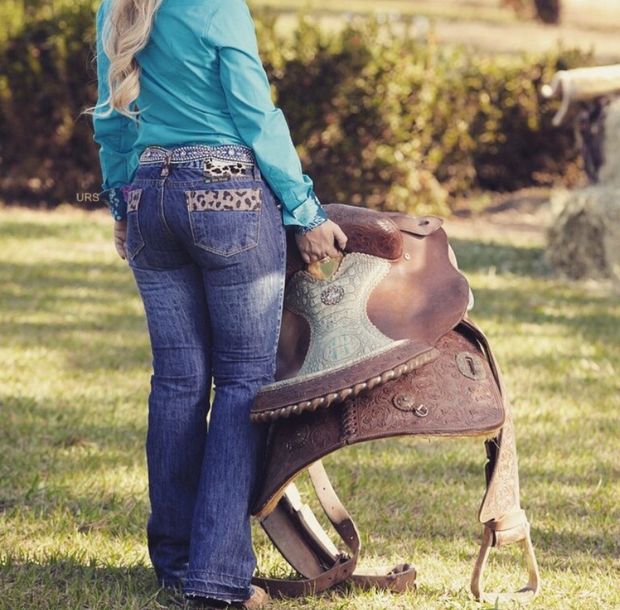 Sexy blonde cowgirl in tight jeans with her saddle