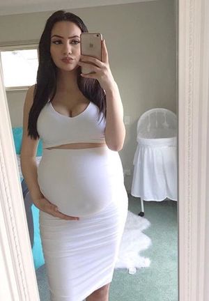 Pregnant belly in a tight white dress