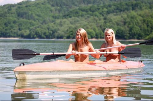 A couple of naked kayakers out on a lake.