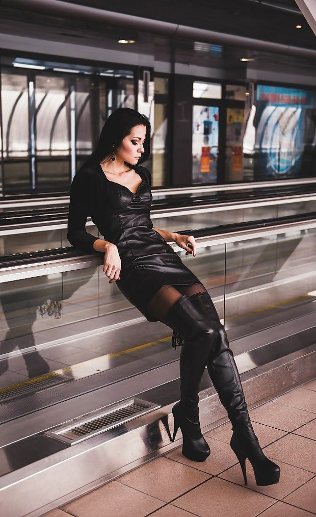Damn hot babe posing in tight black leather dress and high heeled boots