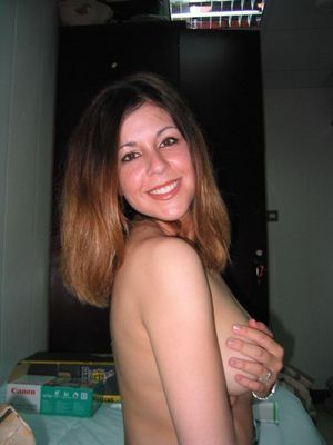 Smiling chick covers natural breasts