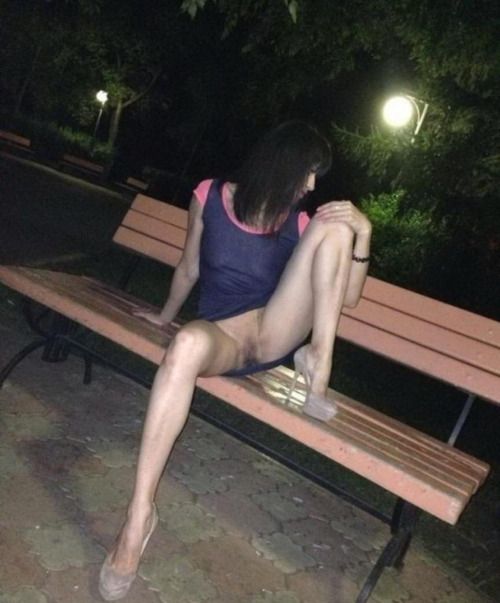 Teen chick shows shaved pussy while sitting on a park bench
