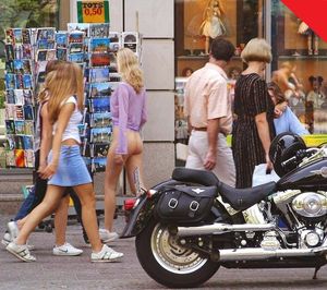 Bottomless babe shops for postcards in busy street.