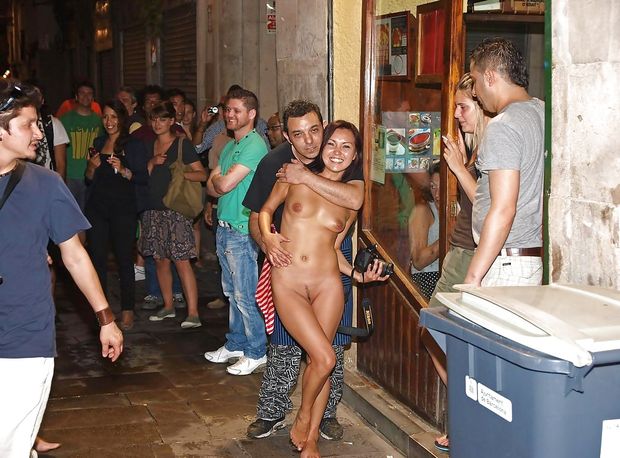 He is showing her off naked on the crowded street.