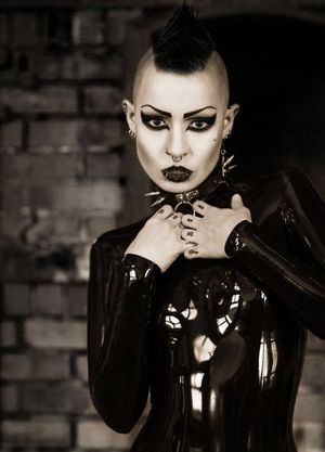 Toxic Devil is a sinister yung goth model in black latex with her weird hair emo mo hawk - fota lett gothh ppale collar