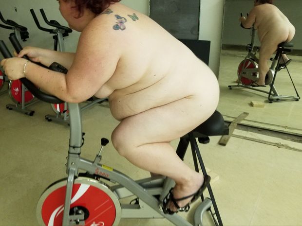 BBW riding exercise bike nude by a mirror
