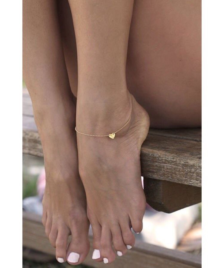 Beautiful tanned slender feet with anklet and painted nails.