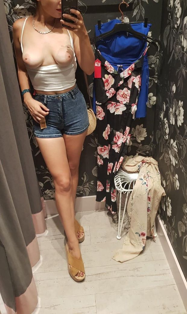 cute woman in jean shorts flashing her tits in a dressing room