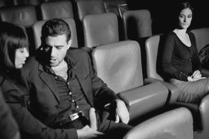 At a movie theater watching her husband