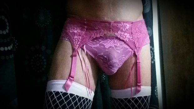 Pink suspenders with pink large fishnets over black stockings