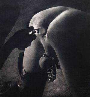 domina inserts a plug in her submissive's asshole in chastity cage