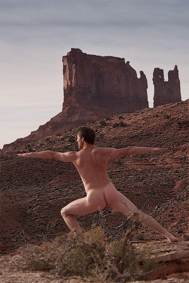 nude male doing warrior pose in desert