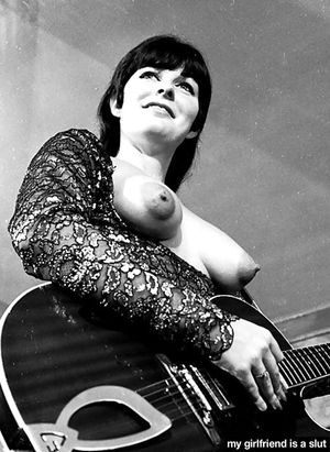 Guitarist smiles with her tits out.