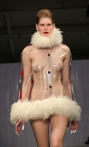 Walking the runway in a strange clear dress with fake fur trim.