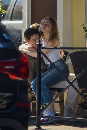 Sabrina Carpenter braless boobs in a white tank top showing off her tits also sitting in her boyfriends lap kissing seen by paparazzi.