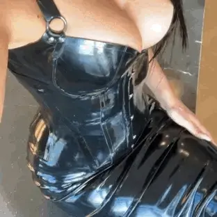 sexy babe wearing black latex dress/corset thats got her boobs pushed up & looking fabo