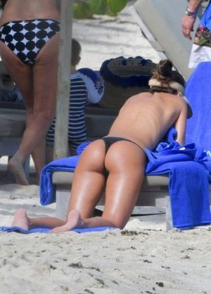 Izabel Goulart topless tanning at the beach covering her nude boobs with a towel showing off her sexy ass in a thong bikini.