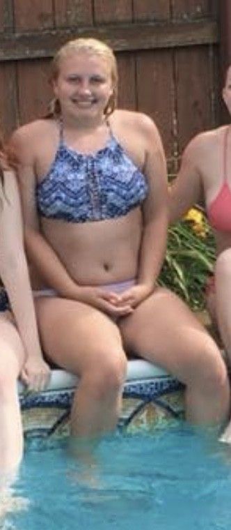 Teen sitting on the edge of the pool with her hands in her lap