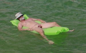 nude male sunbathing on lake