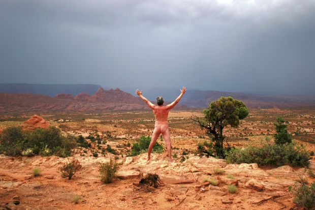 nude male in desert worshipping rain clouds