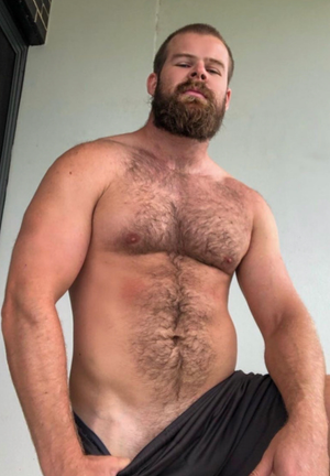 Hairy bear smirks showing off tan line