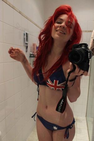 Redhead takes picture in bikini in front of mirror.