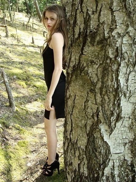 Insta babe posing outdoors in black satin mini dress and heels