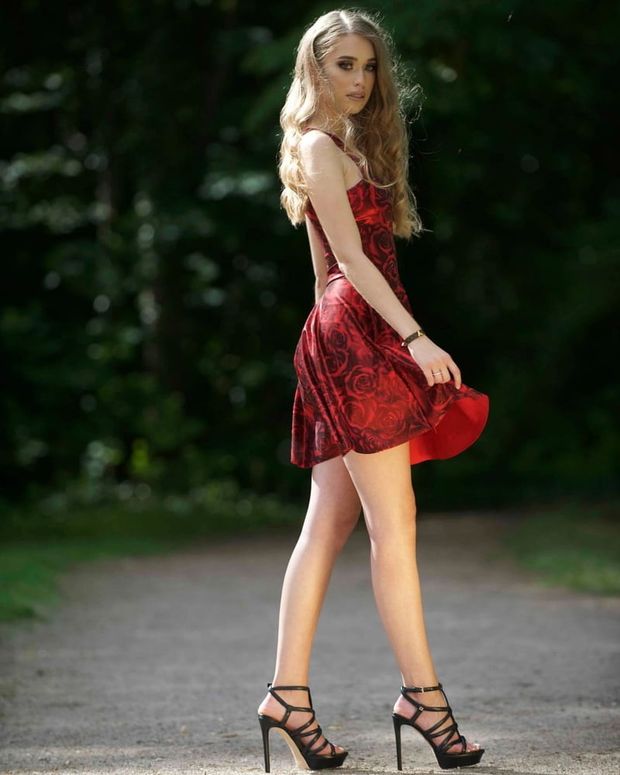 Leggy babe posing outdoors in sexy red dress and high heeled sandals