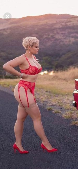 Busty blonde in red lace lingerie, tan stockings and red high heels, outdoor