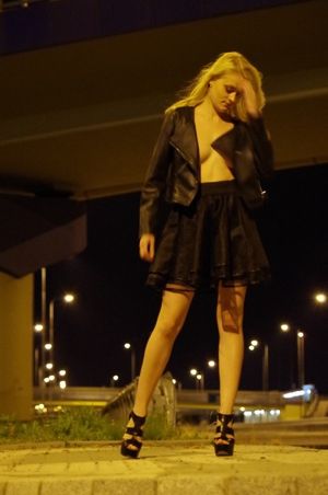 Blonde chick posing outdoors braless in leather jacket and flared mini skirt