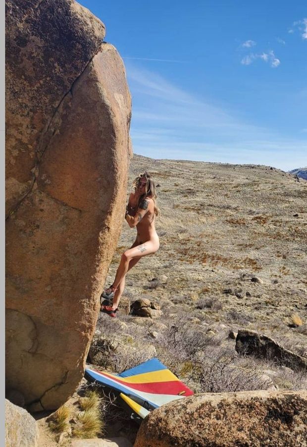 Nude woman bouldering in the sun.