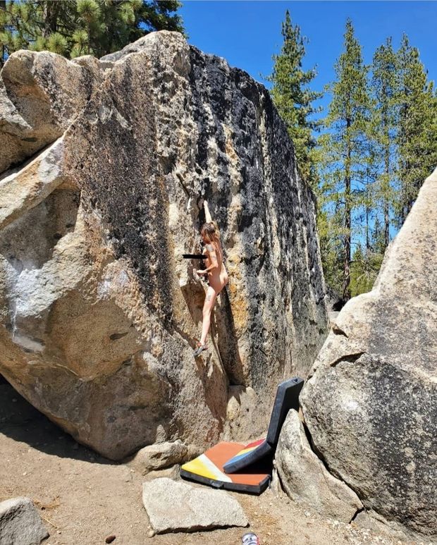 Nude woman climbing hard boulder route.