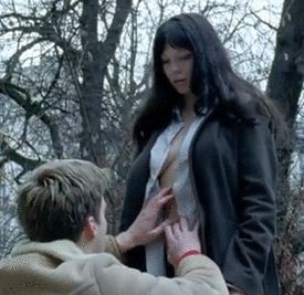 Kneeling man opens up Léa Seydoux's shirt to expose her boobs.