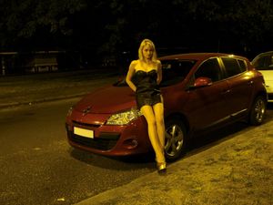 Hot blonde babe in tight short leather dress posing outdoors