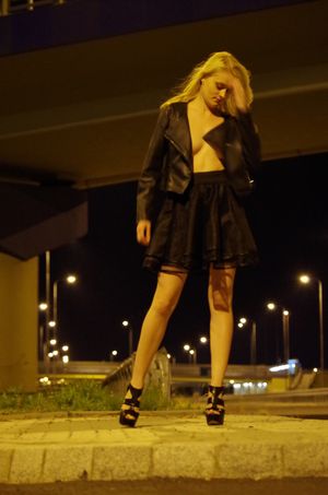 Leggy blonde outdoors topless in loose black skirt and jacket