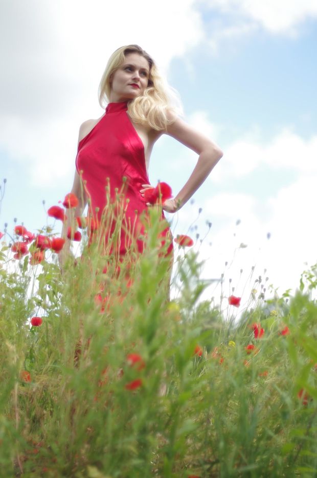 Blonde model posing braless outdoors in satin red dress
