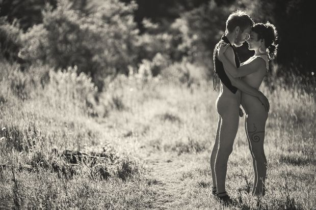 Nude couple holding each other outdoors