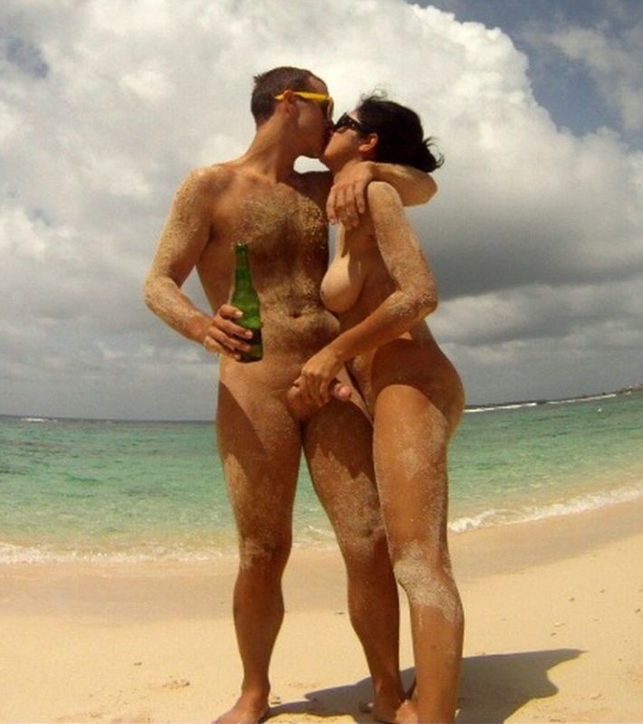 At the beach with a beer in hand and a hand on his cock