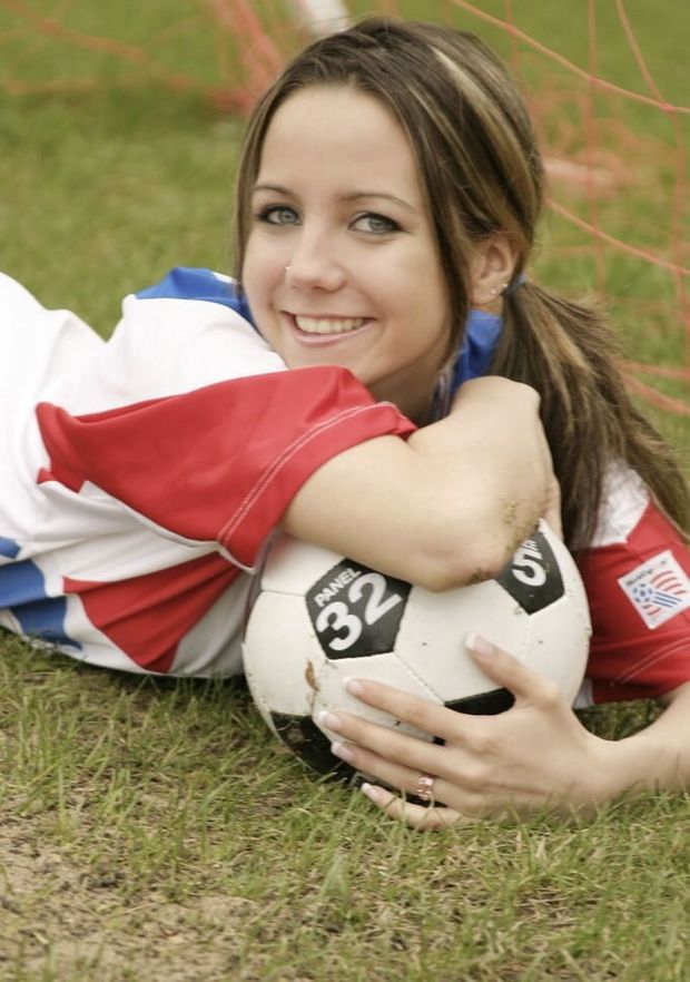 Cute brunette with her arm on top of a soccer ball