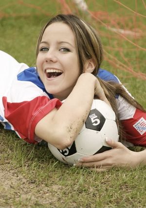 Cute brunette with a soccer ball under her arm