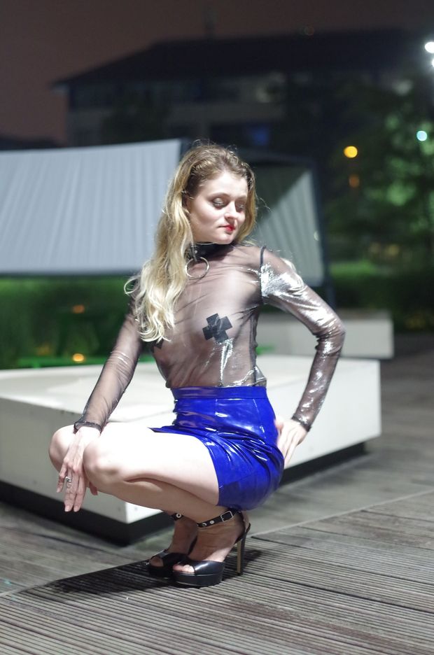 Hot blonde model Veronica posing outdoors in latex mini skirt and shiny sheer blouse