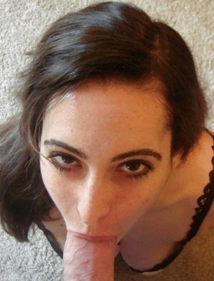 Brunette on her knees looking up and sucking cock