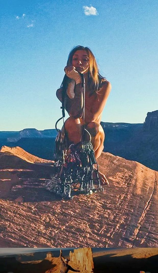 Nude rock climber squats behind her rack