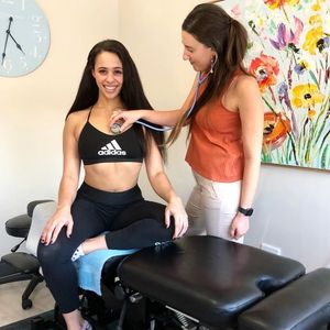 Chick in sports bra having her heart listened to with a stethoscope