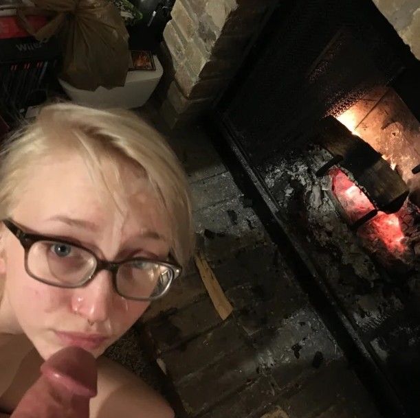 Adorable blond teen getting a load on her face by the fireplace