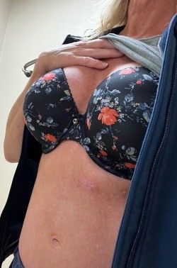 Mature nurse lifting up her shirt and flashing her bra.