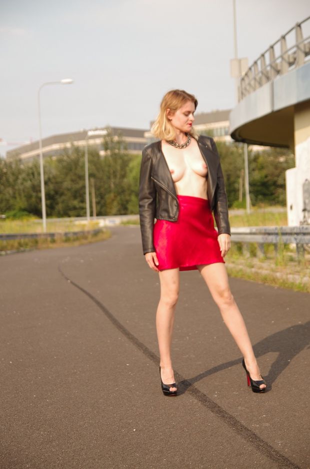 Cute blonde posing outdoors braless in sexy little red skirt and jacket