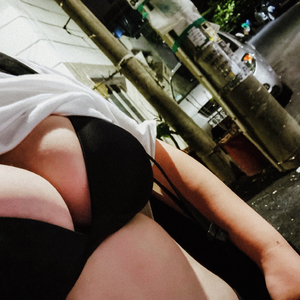 Lifting up her shirt to reveal her Black bra