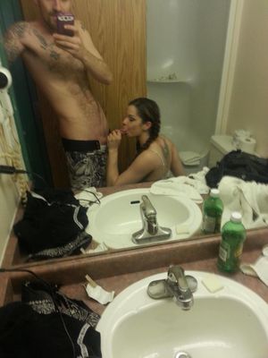 Mirror-shot in the bathroom of a brunette sucking on dick