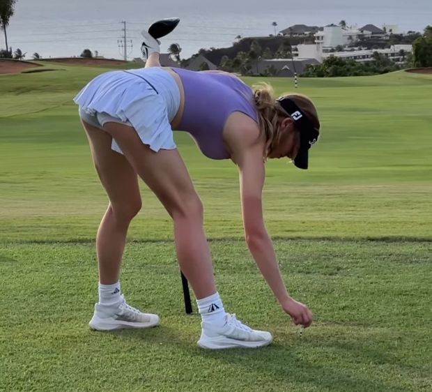 Grace bending over putting a golf ball down